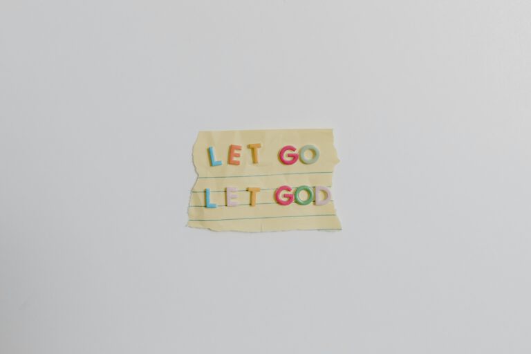 Minimalist image of a torn paper with the phrase 'Let Go, Let God' in colorful letters.