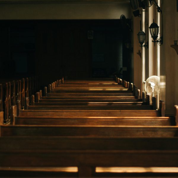 Serene church interior featuring wooden pews and beautiful lighting casting shadows through windows.
